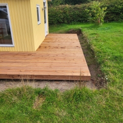 Hævet træterrasse med trappe og sort rækværk