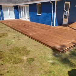 træterrasse ved blåt hus med havedøre og hvid tagrende