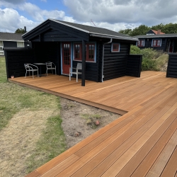 Træterrasse ved hvid mur og sort hus