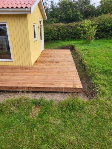 Hævet træterrasse med trappe og sort rækværk