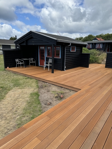 Træterrasse ved hvid mur og sort hus